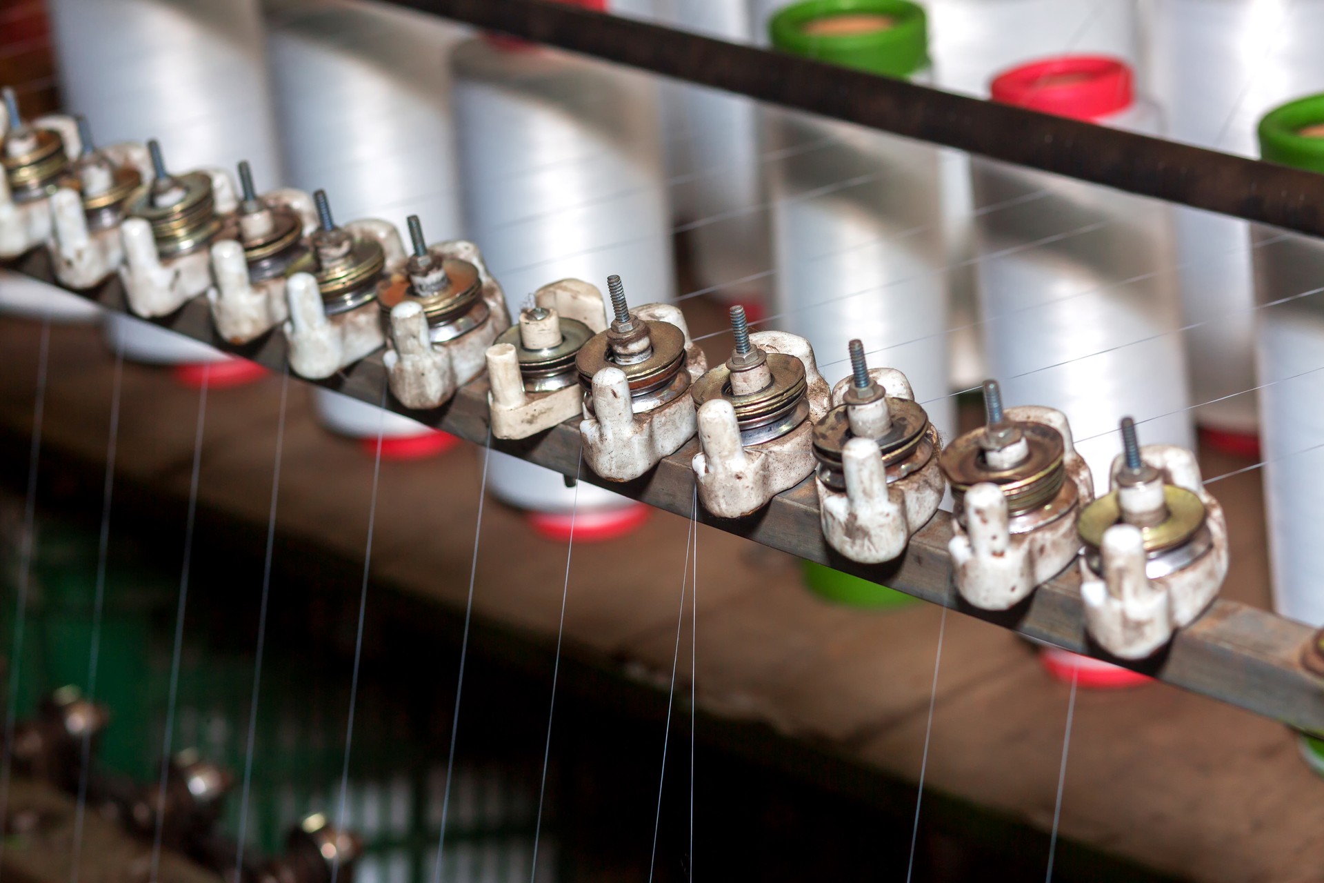 Red-green spools of white yarn in a garment factory. Weaving loom in a textile factory.